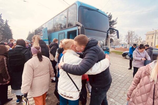 Menschen umarmen sich vor einem Reisebus.