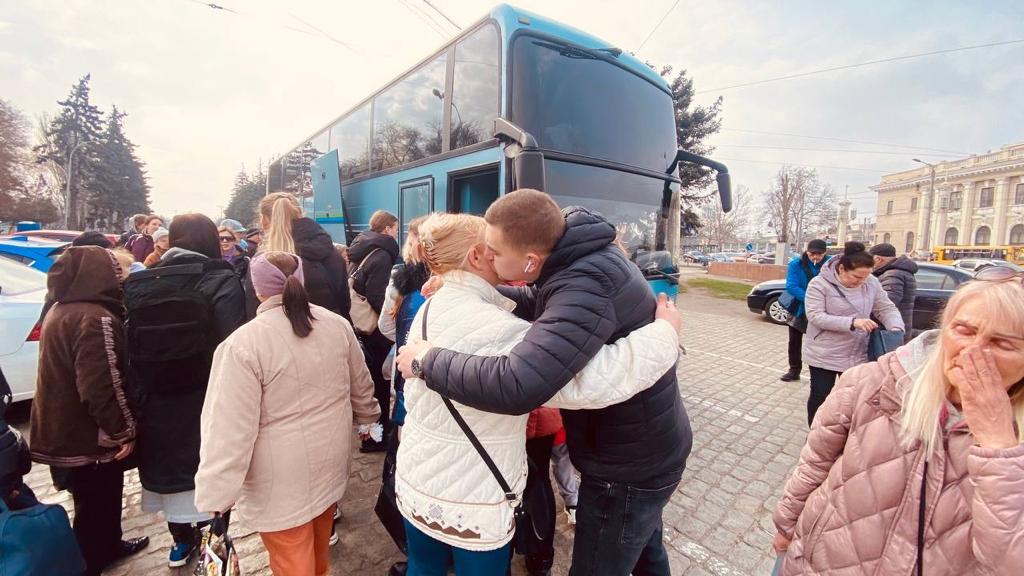 Menschen umarmen sich vor einem Reisebus.